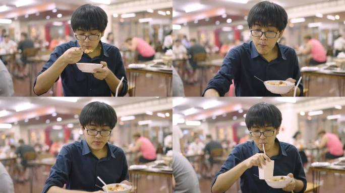 一个戴眼镜的亚洲人在中餐馆里吃喝