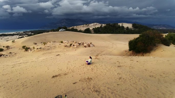 在海边的沙丘上以莲花的姿势冥想。无人机航拍图。帕塔拉沙丘。火鸡