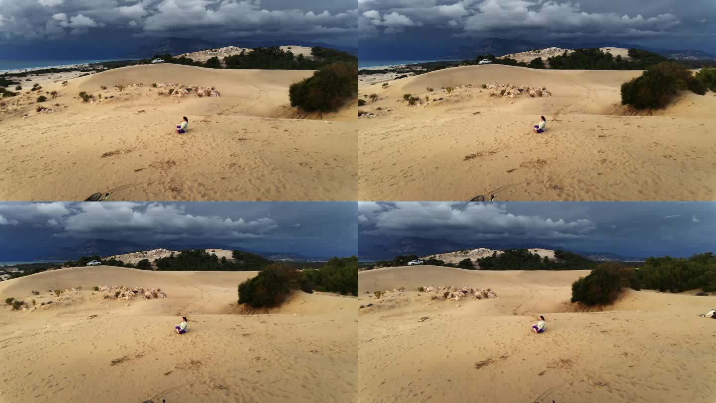 在海边的沙丘上以莲花的姿势冥想。无人机航拍图。帕塔拉沙丘。火鸡