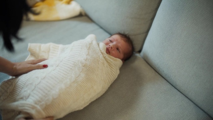 妈妈用毯子把婴儿包起来。刚出生的婴儿被母亲用毯子包裹在家里。