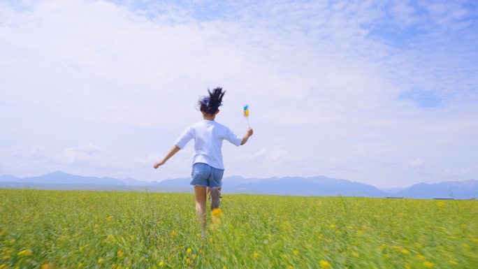 小女孩拿着风车奔跑在田野上