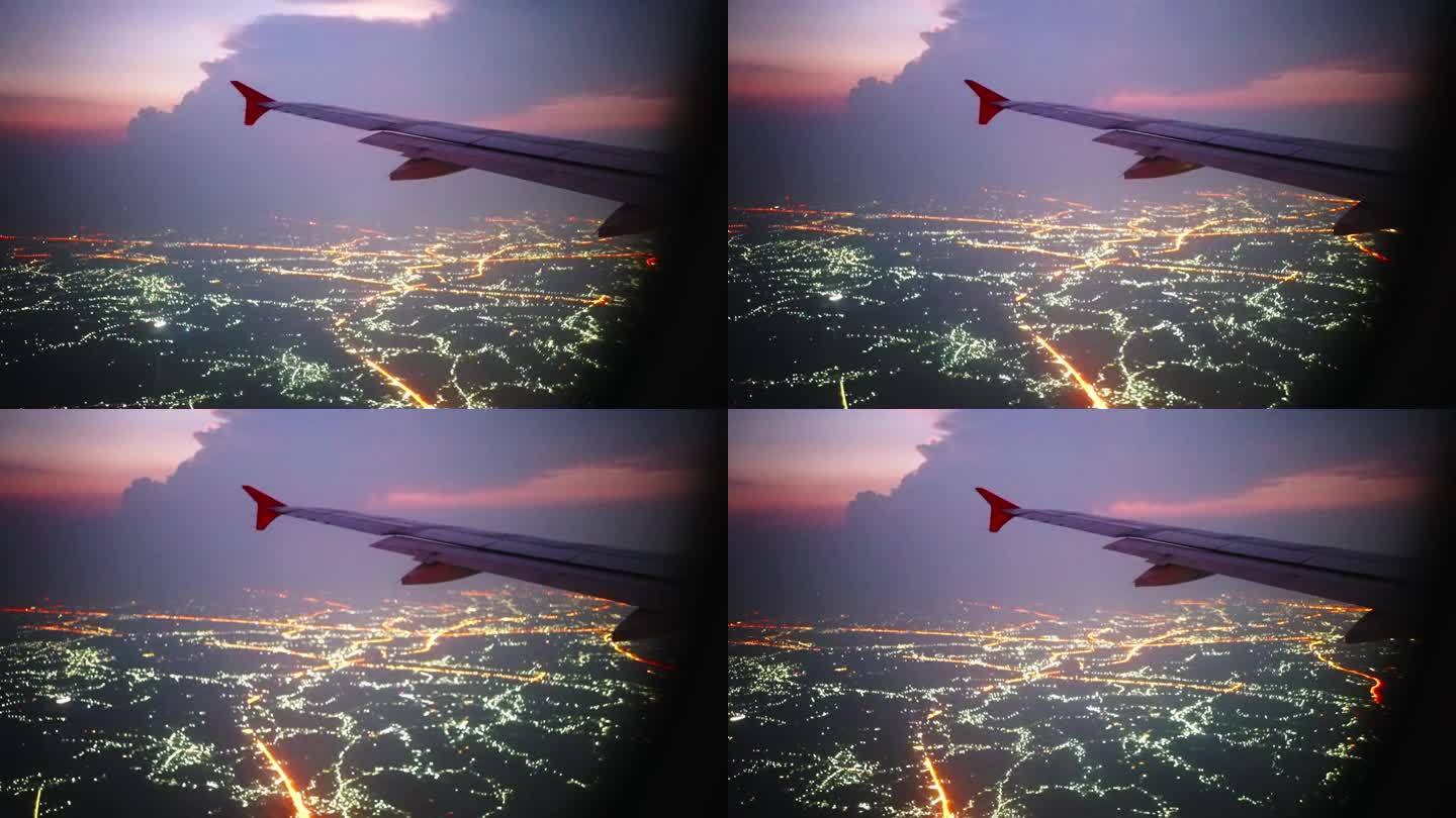 黄昏时分，在飞机上欣赏美丽的天空和城市的灯光。从窗口拍摄