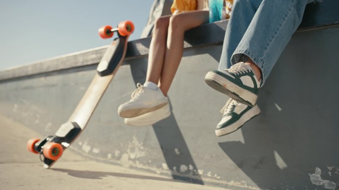 鞋，让滑板的年轻人和滑板在城市的一块滑板上自由地结合在一起。滑冰，休息和屋顶上的城市建筑坐在墙上的腿