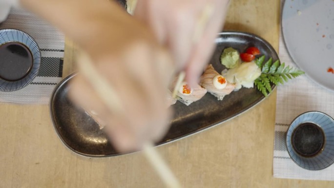 两个朋友在日本餐馆里为争夺中间一块鲑鱼寿司而嬉戏的高角度视角