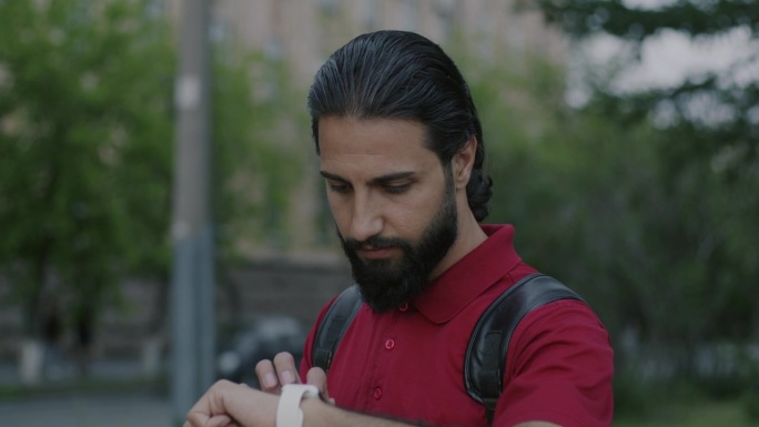 中东男子站在城市街道上使用智能手表触摸设备的肖像