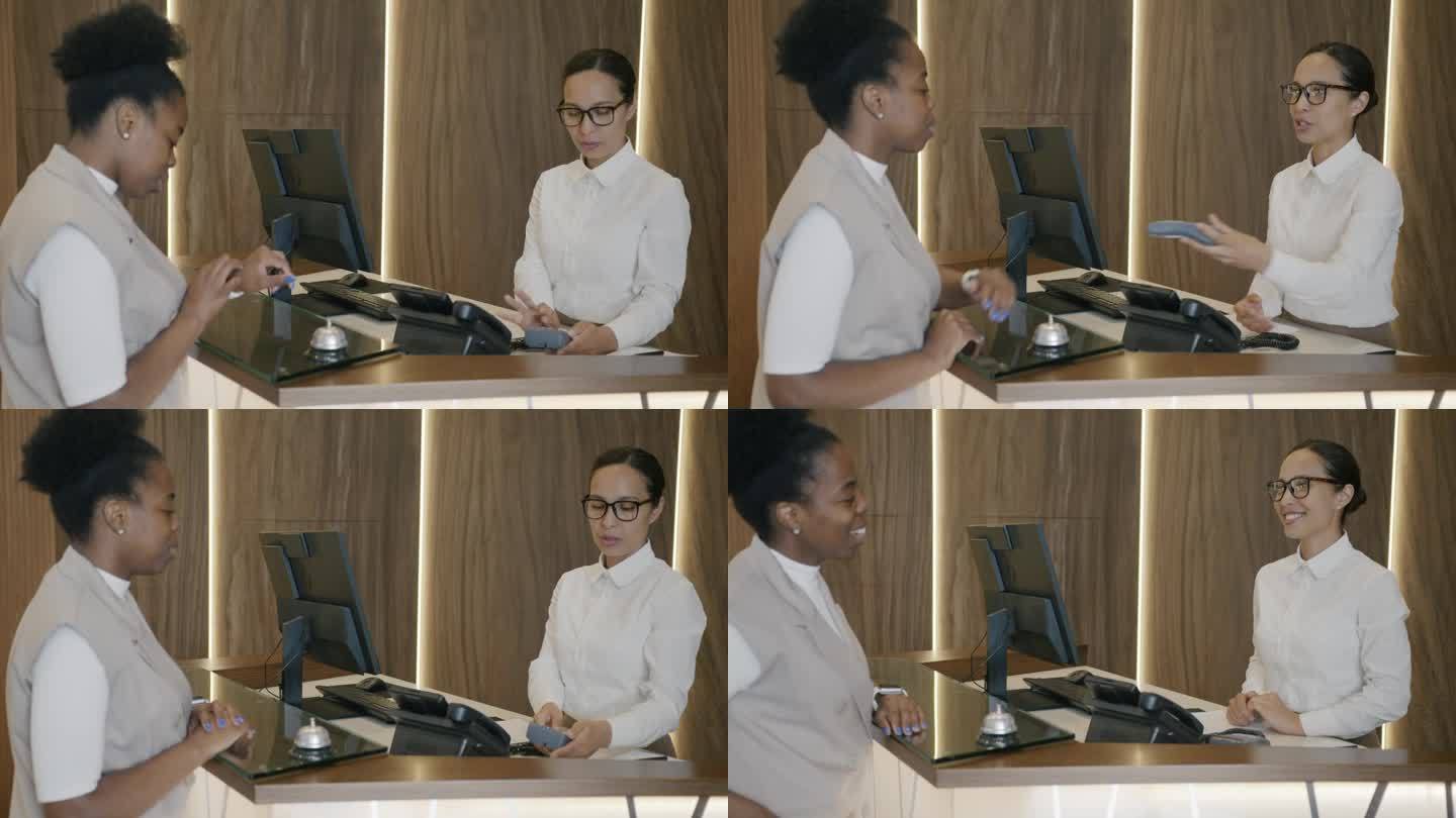 非裔美国女商人与酒店接待员交谈，然后用智能手表付款