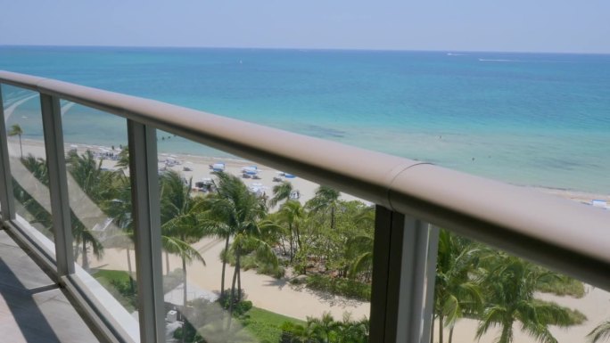 从迈阿密豪华度假胜地高层公寓的露台上欣赏迷人的景色。热带海滩与异国情调的棕榈树，大西洋清澈的海水和白