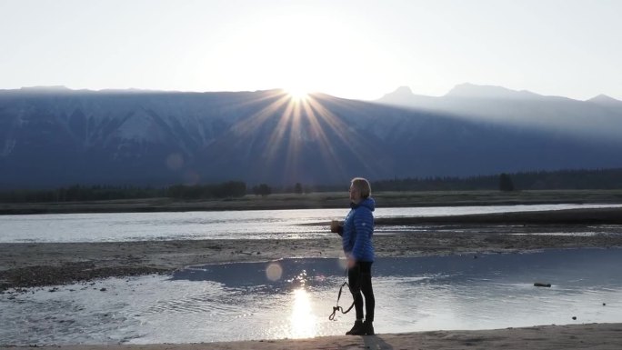 女人在清晨走在湖边，看日出