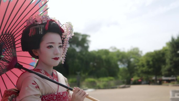 日本舞伎(艺伎在训练)站在公园在祗园，京都-拿着日本传统的纸伞