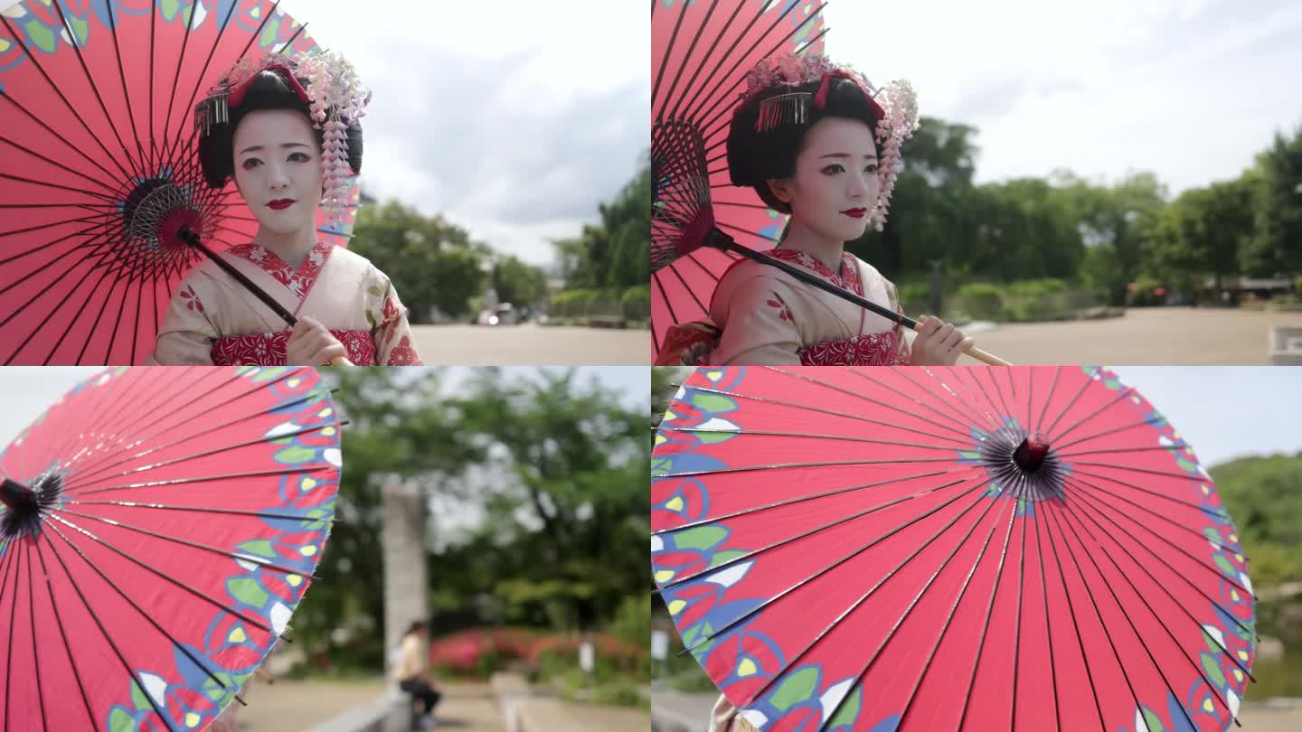 日本舞伎(艺伎在训练)站在公园在祗园，京都-拿着日本传统的纸伞