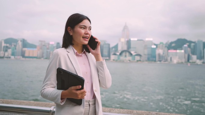 走在香港商业中心中心的女商人用你的手机来协调工作。