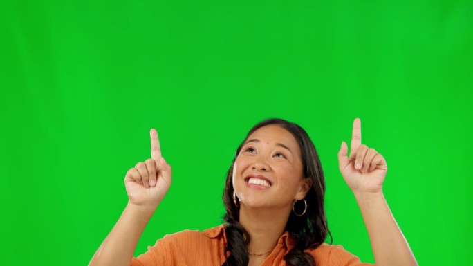 快乐的亚洲女人，指着绿色的屏幕和营销工作室的背景。女性负责市场广告，促销折扣或交易的通知，提醒或实物