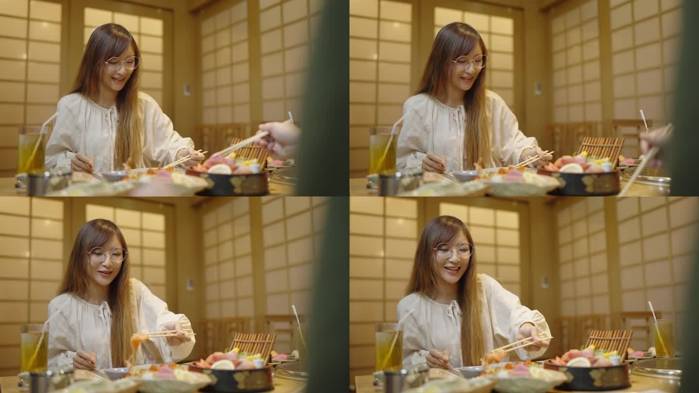 美丽的长发女人和她的朋友在日本餐厅吃生鱼片的中镜头