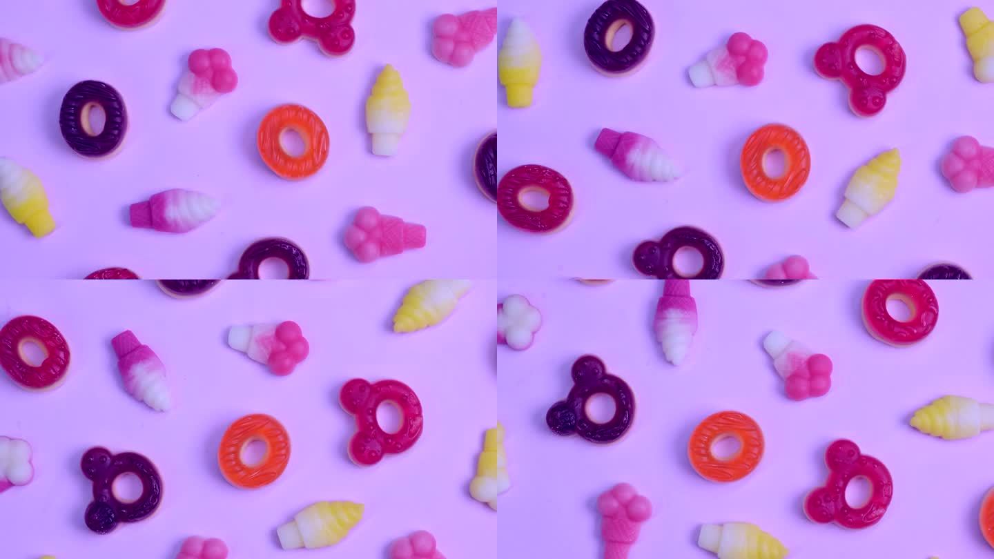旋转背景的各种果冻糖果，熊，甜甜圈，糖果，粉红色的背景特写顶视图概念生日聚会或庆祝活动