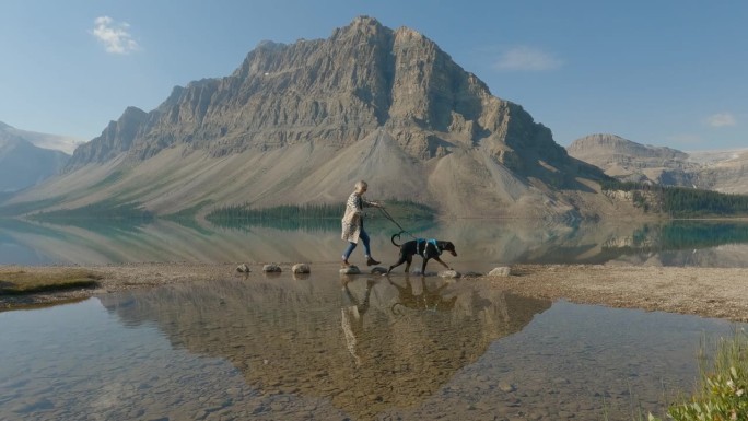 一个女人在山间湖滨用皮带遛狗