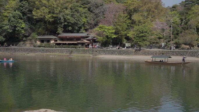 游客们在岚山河上乘船欣赏樱花