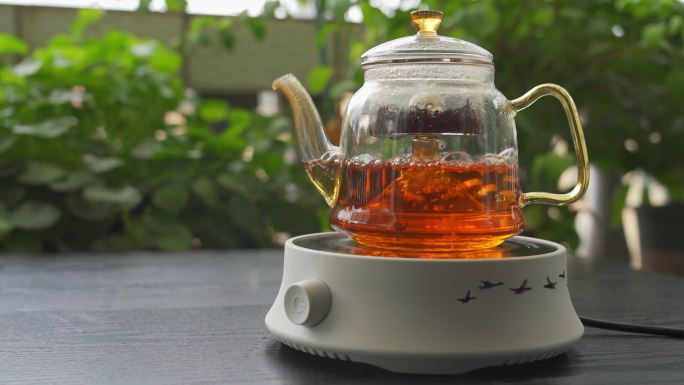 在漂亮的花园里用电炉玻璃茶壶煮红茶