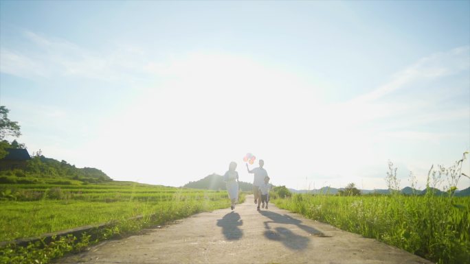 一家三口拿着彩色气球逆光奔跑幸福家庭温馨