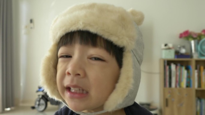 快乐的小男孩戴着帽子在家里玩耍和微笑，慢动作的场景