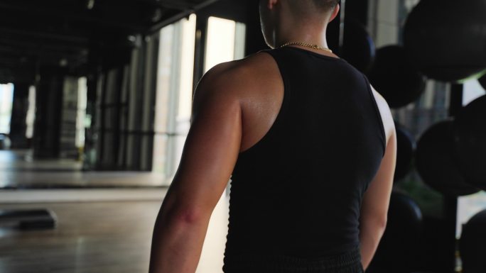 身材健硕年轻男人走在健身房锻炼身体的背影