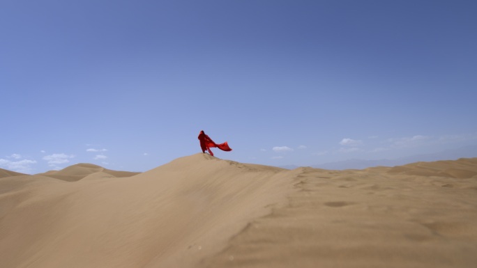 一个身穿红裙的女士在沙漠上行走奔跑沙漠
