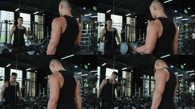 年轻男人在健身房锻炼身体面对镜子练习举重