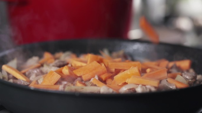 在锅里煎肉的胡萝卜落下的慢动作