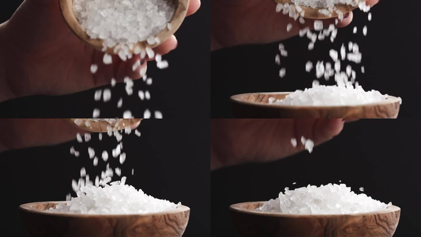 粗糙的海盐晶体从一个碗慢慢地落到另一个碗中