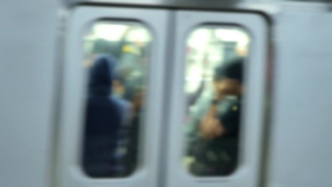 夜间在雅加达车站，一列移动的通勤列车上的乘客被模糊。描绘下班后火车乘客的密度。