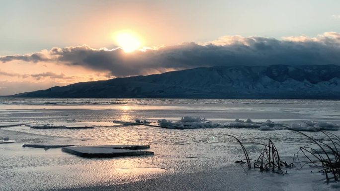 太阳透过云层在冰冻的犹他湖上的日落