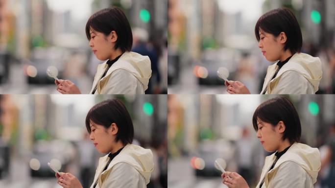 美丽的女人在城市里等红灯的时候用她的智能手机