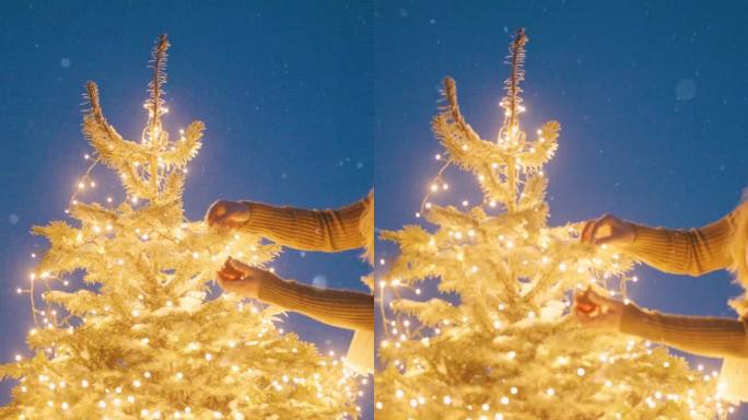 一名妇女将装饰品挂在一棵圣诞树上，这棵圣诞树生长在白雪覆盖的林间空地中央