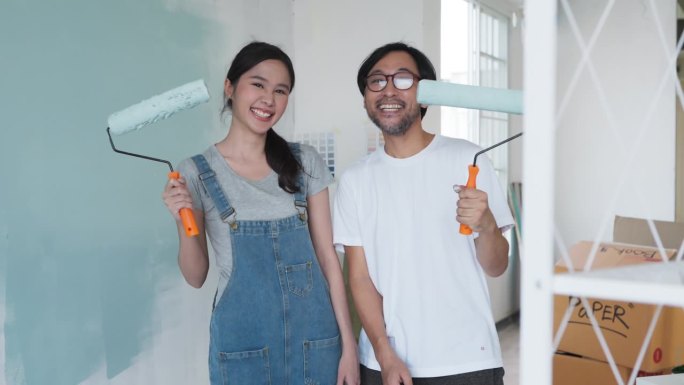 幸福休闲放松亚洲夫妇装修客厅和舞蹈一起装修工具。公寓装修和房屋装修的同时进行。装修家居