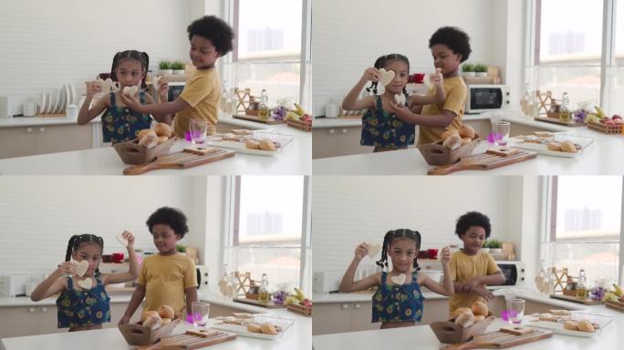 快乐的孩子们在厨房里制作和吃心形三明治