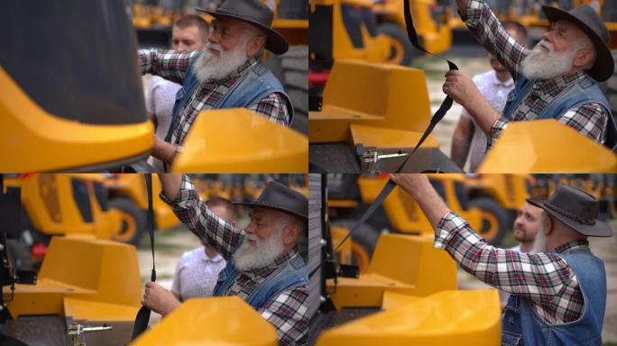 老人打开巨大拖拉机的前部，在外面和年轻人交谈。经验丰富的专业高加索农民与同事一起选择新车。缓慢的运动
