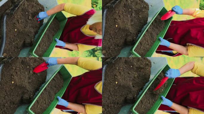 一个女人的手往一个长长的绿色花盆里倒土的特写