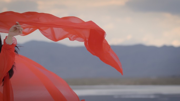 一个身穿红色长裙的女人站在湖中红裙