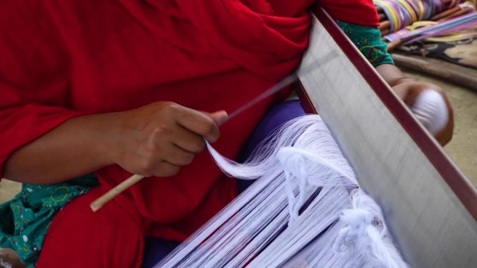 一个女人的手把纱线平行于织布的钢线。