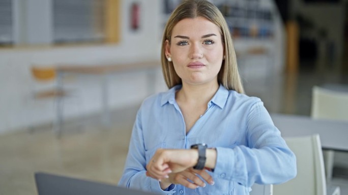 年轻的金发女商务人员看着手表，在办公室跟老板说不