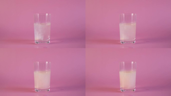 草莓味的维生素C片泡沫化在粉红色背景的玻璃杯中冒泡。乙酰水杨酸泡腾片溶于水，形成许多嘶嘶的气泡