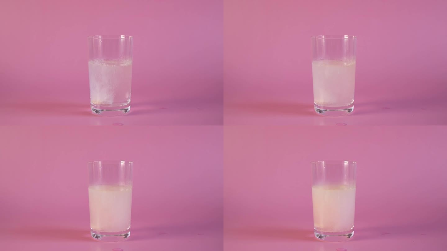 草莓味的维生素C片泡沫化在粉红色背景的玻璃杯中冒泡。乙酰水杨酸泡腾片溶于水，形成许多嘶嘶的气泡