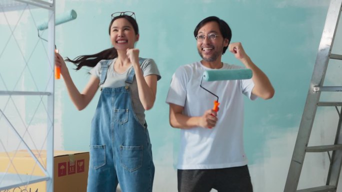 幸福休闲放松亚洲夫妇装修客厅和舞蹈一起装修工具。公寓装修和房屋装修的同时进行。装修家居