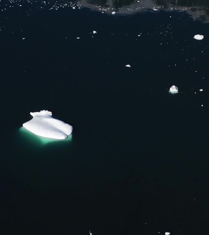在南极洲黑暗的水域中，孤独的船只在冰山附近航行。