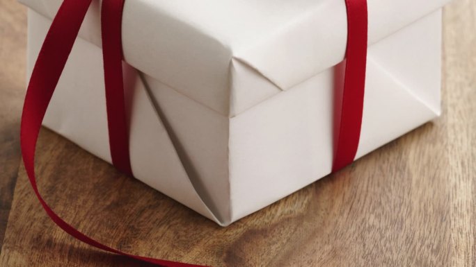 特写的白色纸礼盒薄红丝带蝴蝶结在旧木桌