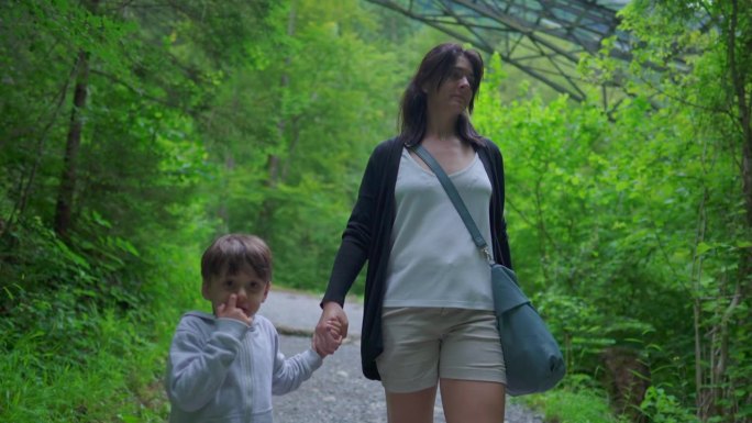 母子一起在森林小径徒步，周末家庭徒步探险，向前走
