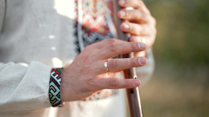 年轻人的手在户外演奏木管木笛-乌克兰索皮卡。民间音乐概念。乐器。身穿传统刺绣衬衫的音乐家。
