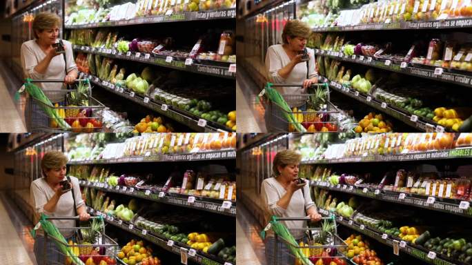 一个成熟的女人一边推着购物车一边讲着免提，一边看着超市冷藏室里的有机蔬菜