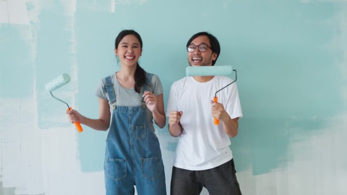 幸福休闲放松亚洲夫妇装修客厅和舞蹈一起装修工具。公寓装修和房屋装修的同时进行。装修家居