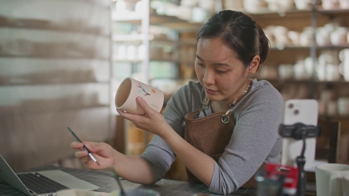 亚洲女艺术家在家庭工作室手绘陶器
