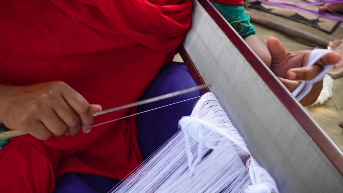 一个女人的手把纱线平行于织布的钢线。